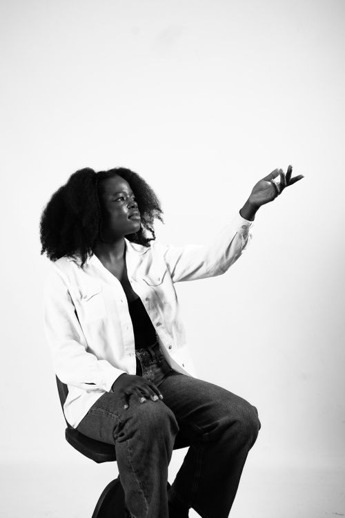 Free Artistic black and white portrait of a woman sitting in a Düsseldorf studio, reaching upward. Stock Photo