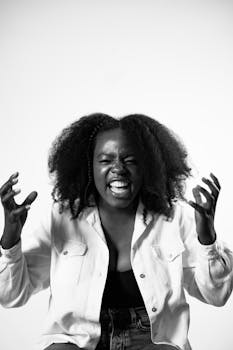 A powerful black and white portrait of a woman expressing strong emotion in a studio setting.