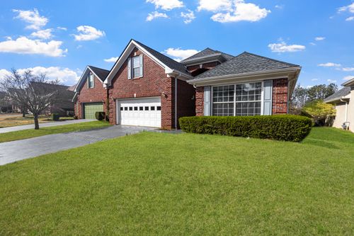 Free Lovely red brick suburban house with a well-maintained lawn under a bright blue sky. Stock Photo