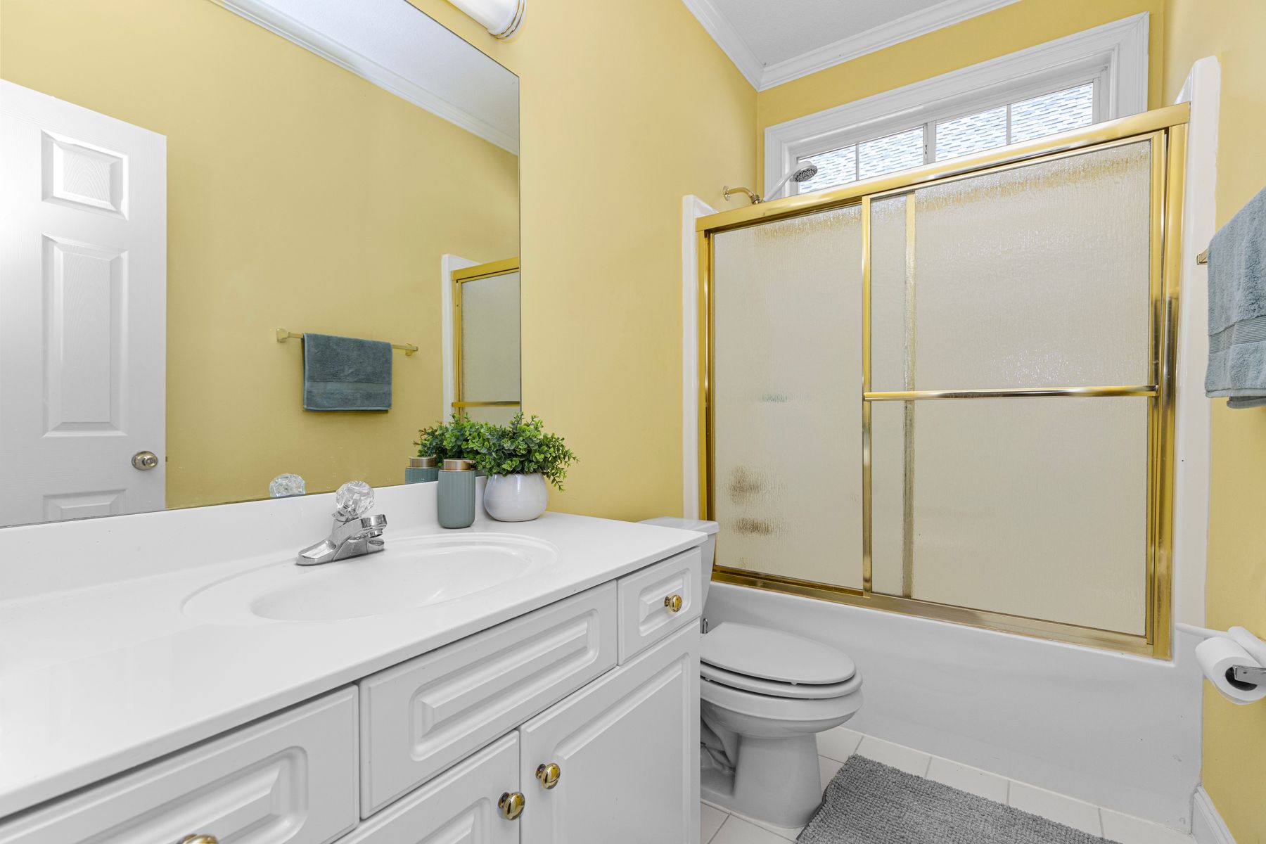 Bright modern yellow bathroom with white fixtures, warm metal details and clean contemporary lines