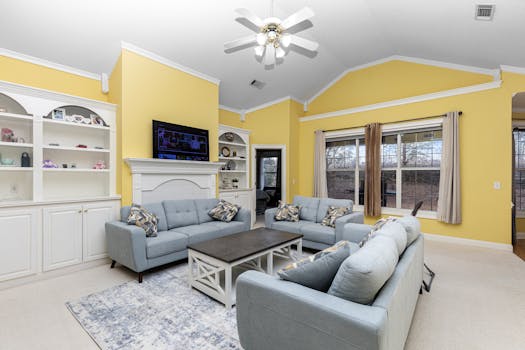 Inviting living room with yellow walls, featuring modern blue sofas and stylish decor.