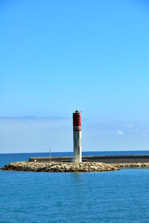 Free A serene lighthouse stands on a rocky coast in Antibes, France, under a clear blue sky. Stock Photo