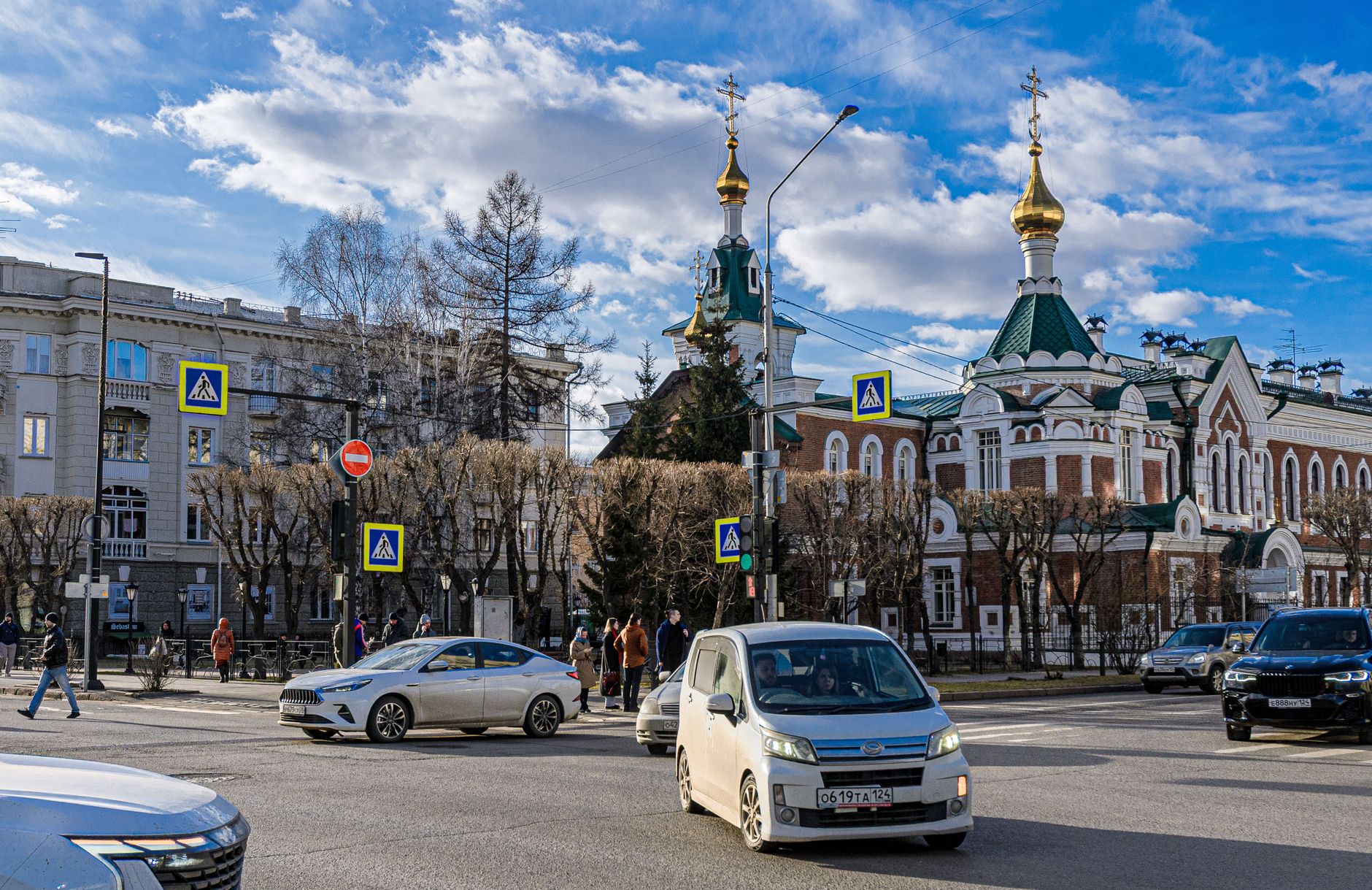 Street scene with historic Eastern European architecture, traffic, and pedestrians on a sunny day.