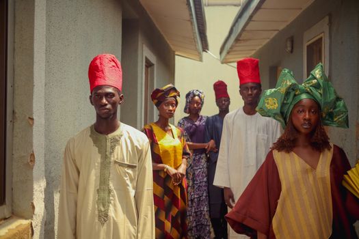 A group of adults in vibrant, traditional attire standing in an alleyway, expressing cultural heritage.