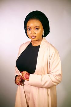 Portrait of a confident woman wearing a headscarf and beige outfit with henna.