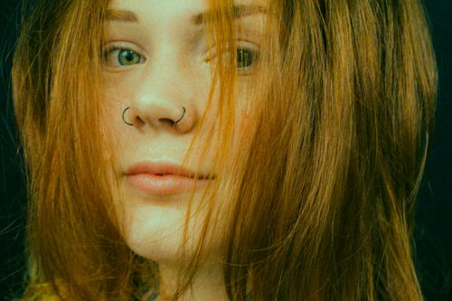 Free Artistic close-up portrait of a woman with red hair and nose rings, evoking a modern and vibrant mood. Stock Photo