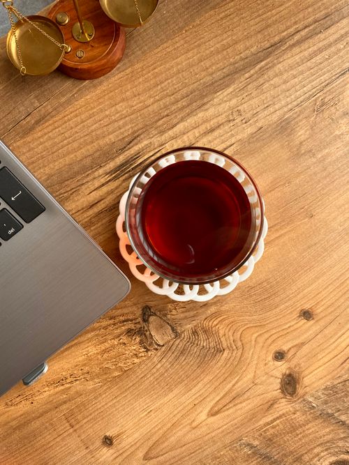 Free A vibrant cup of Turkish tea next to a laptop on a wooden desk, evoking a cozy workspace vibe. Stock Photo