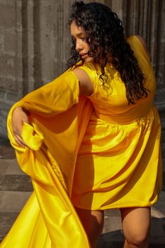Woman in flowing yellow dress dancing gracefully indoors.