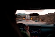 一辆卡车行驶在风景秀丽的公路上，周围环绕着小山