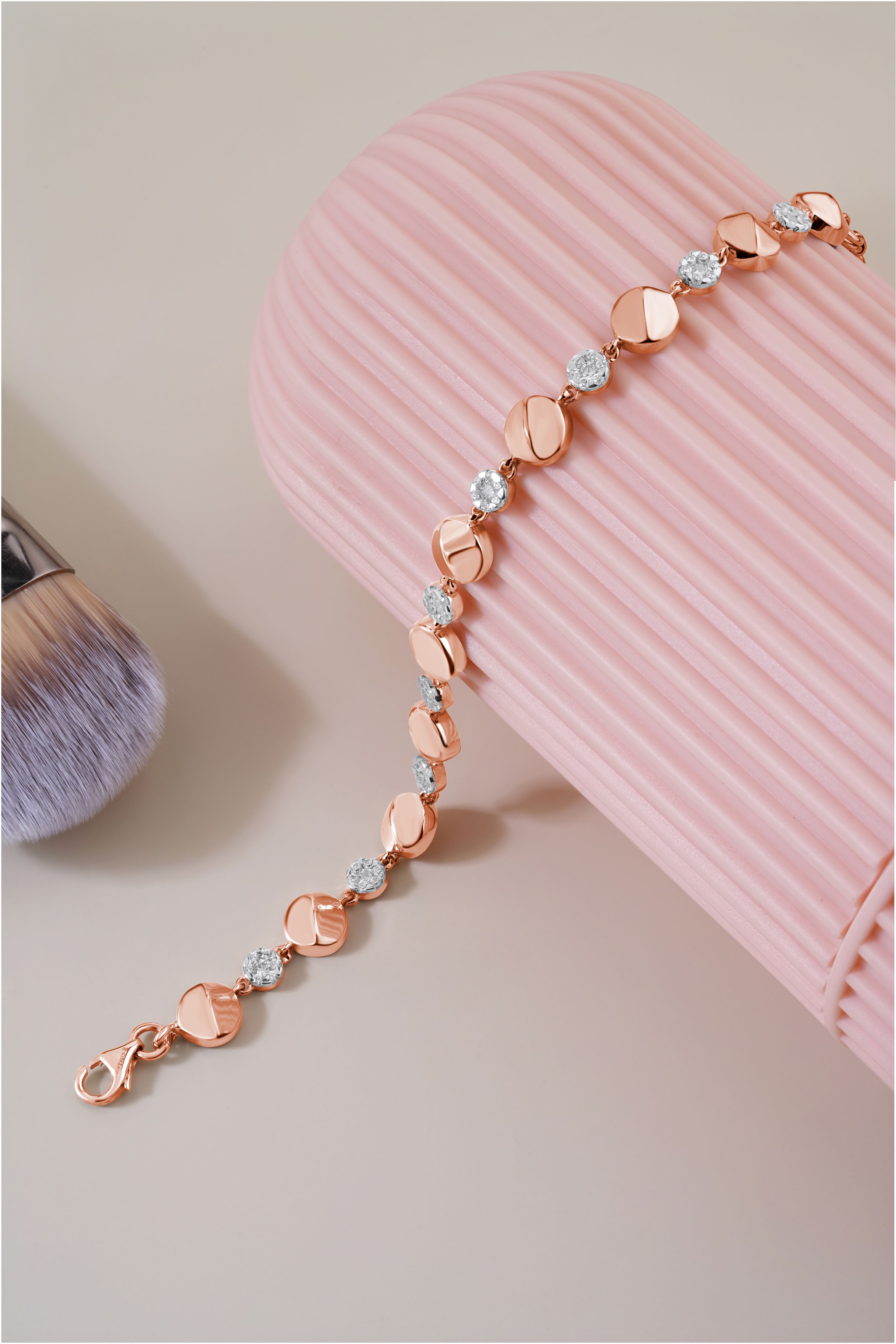 Pulseira de ouro estilosa com diamantes em um fundo rosa, exibindo joias de luxo.