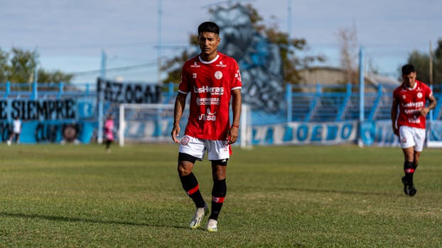 Two soccer players in red jerseys on a grassy field during a match.