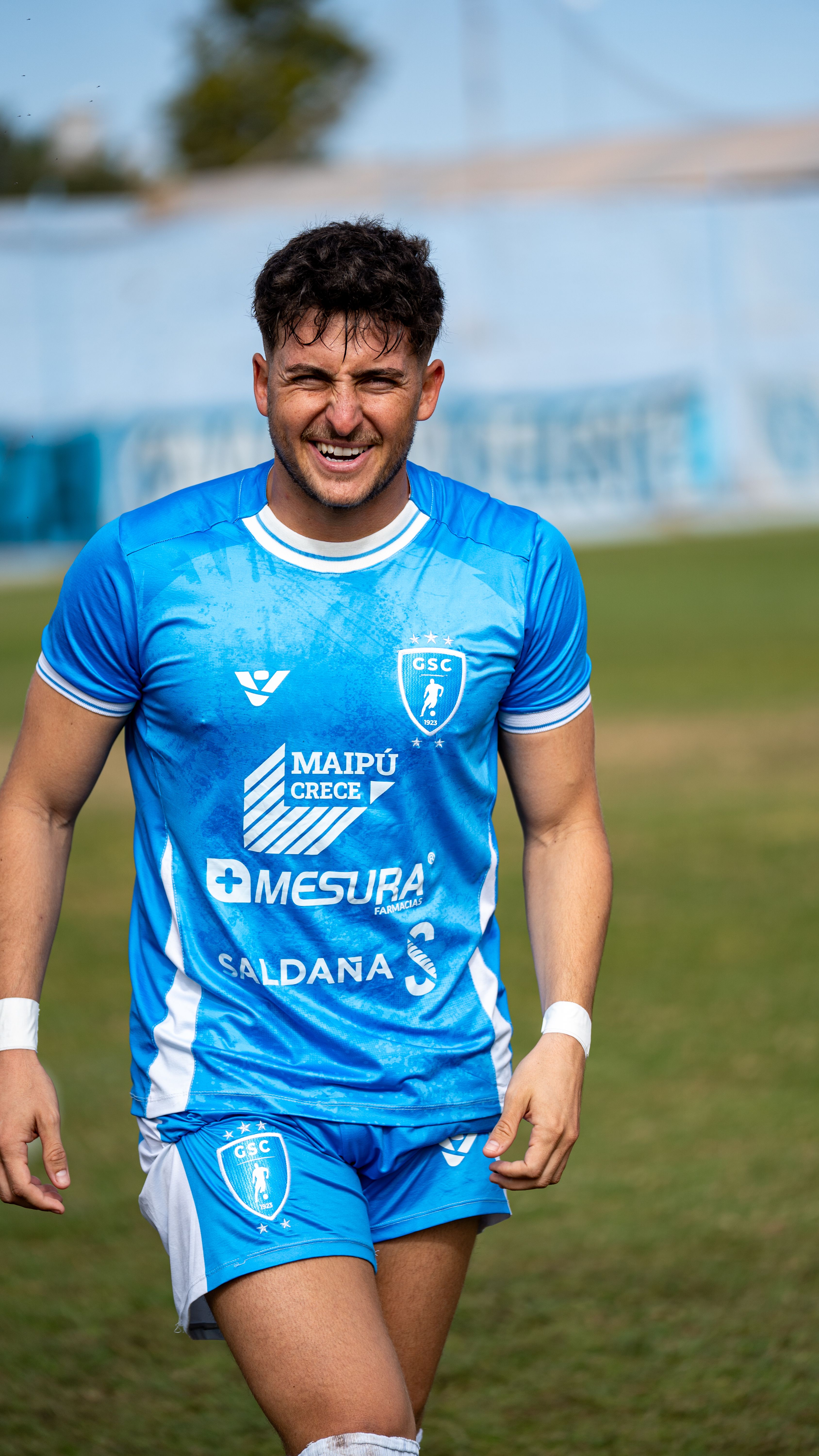 Athlete in blue soccer kit enjoying a game on the field under a clear day.