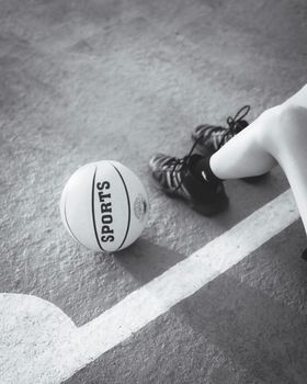Monochrome image of a basketball and shoes on a court, emphasizing sports and readiness.