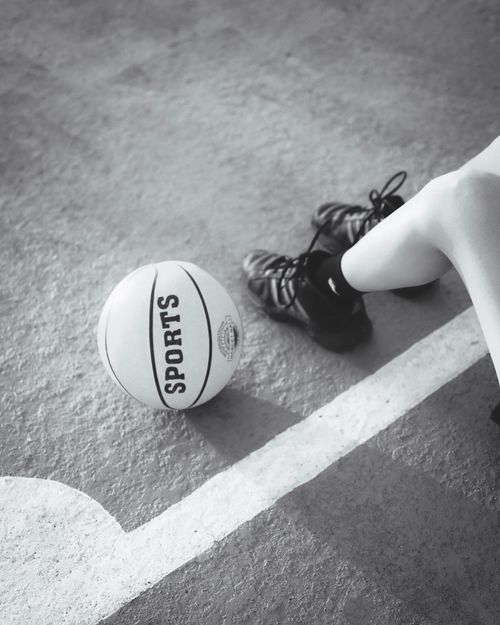 Free Monochrome image of a basketball and shoes on a court, emphasizing sports and readiness. Stock Photo