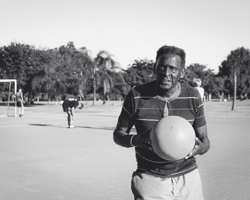 Free A senior man holding a basketball on an outdoor court, exuding determination. Stock Photo