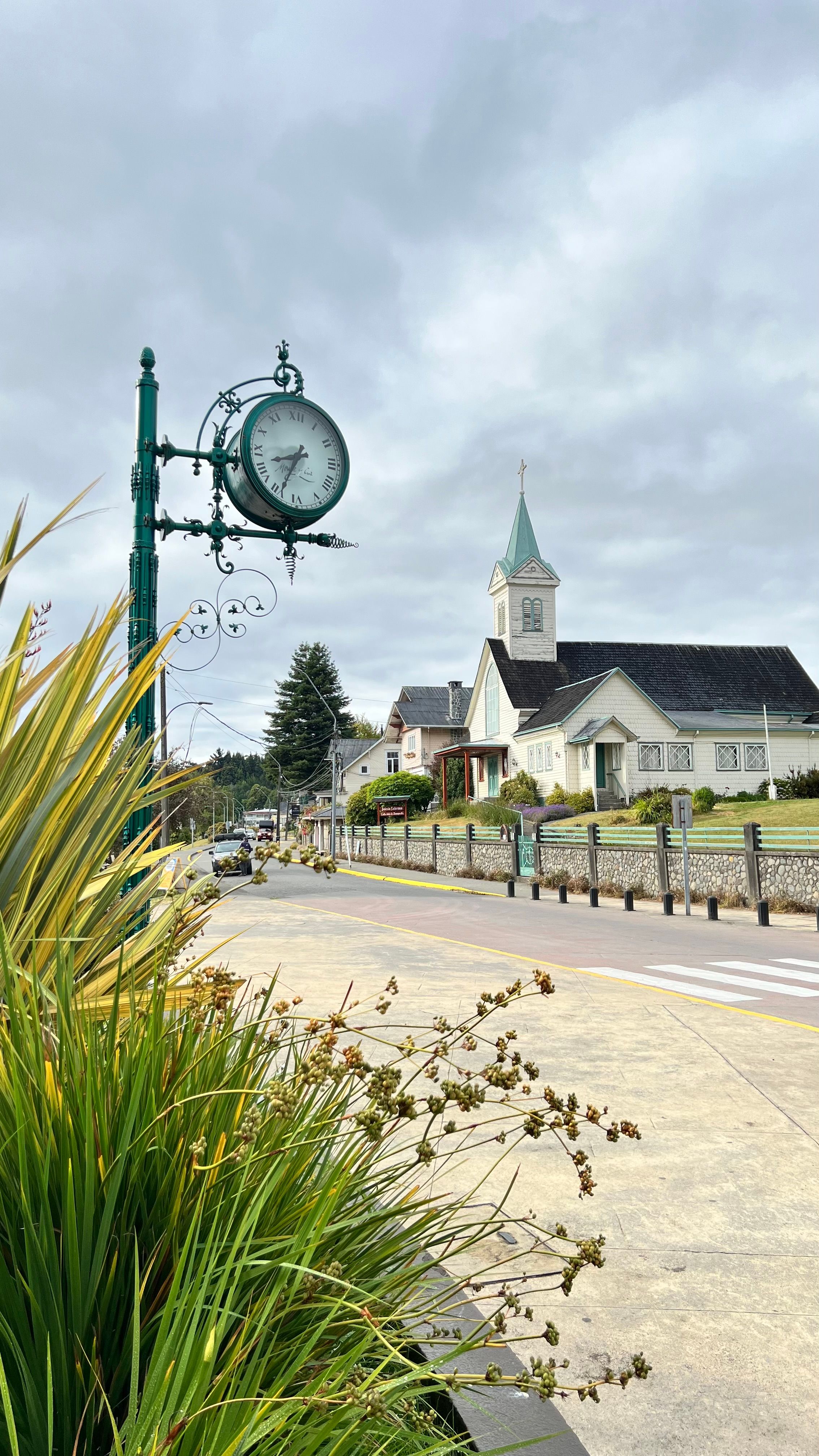 Fotomural Encantadora vista de calle del reloj y la iglesia en Frutillar, Chile, bajo un cielo nublado.