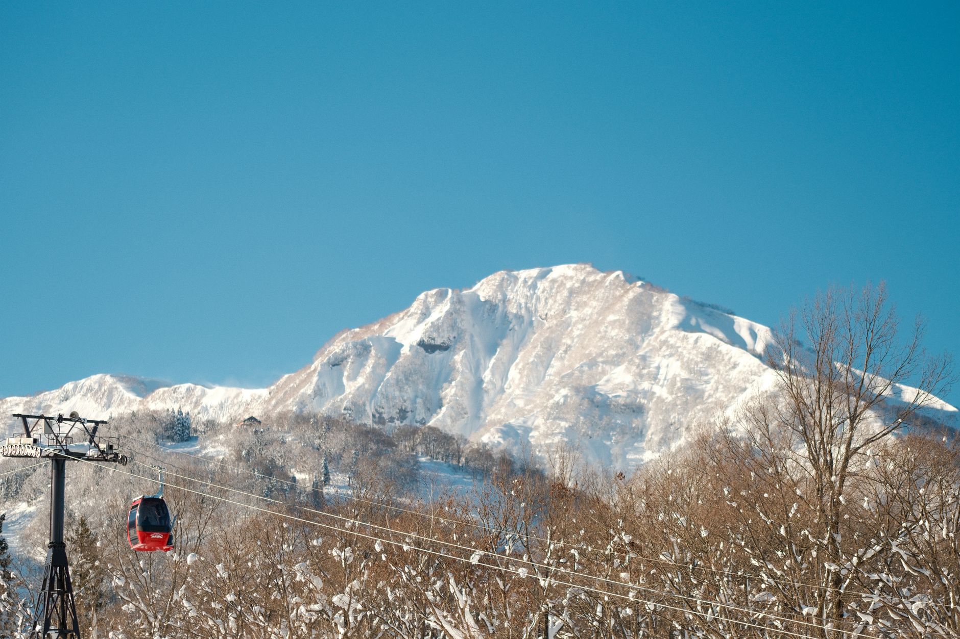 A breathtaking view of a snowy mountain in Japan with a red cable car, perfect for winter travel.