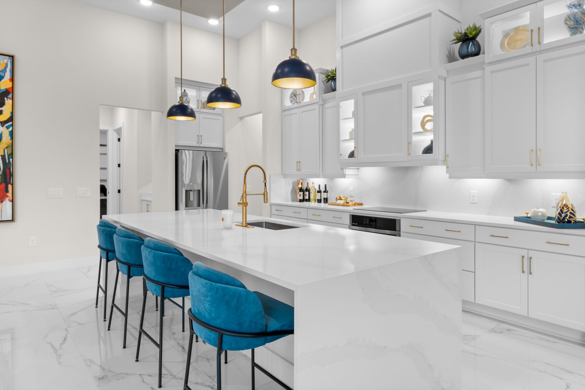 Spacious modern kitchen with white marble countertops and blue velvet bar stools.
