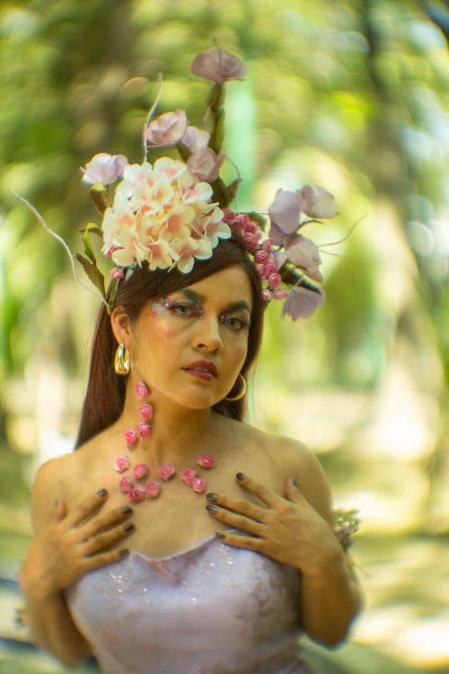 Free Portrait of a woman wearing a floral headdress, captured in a blurred nature setting. Stock Photo