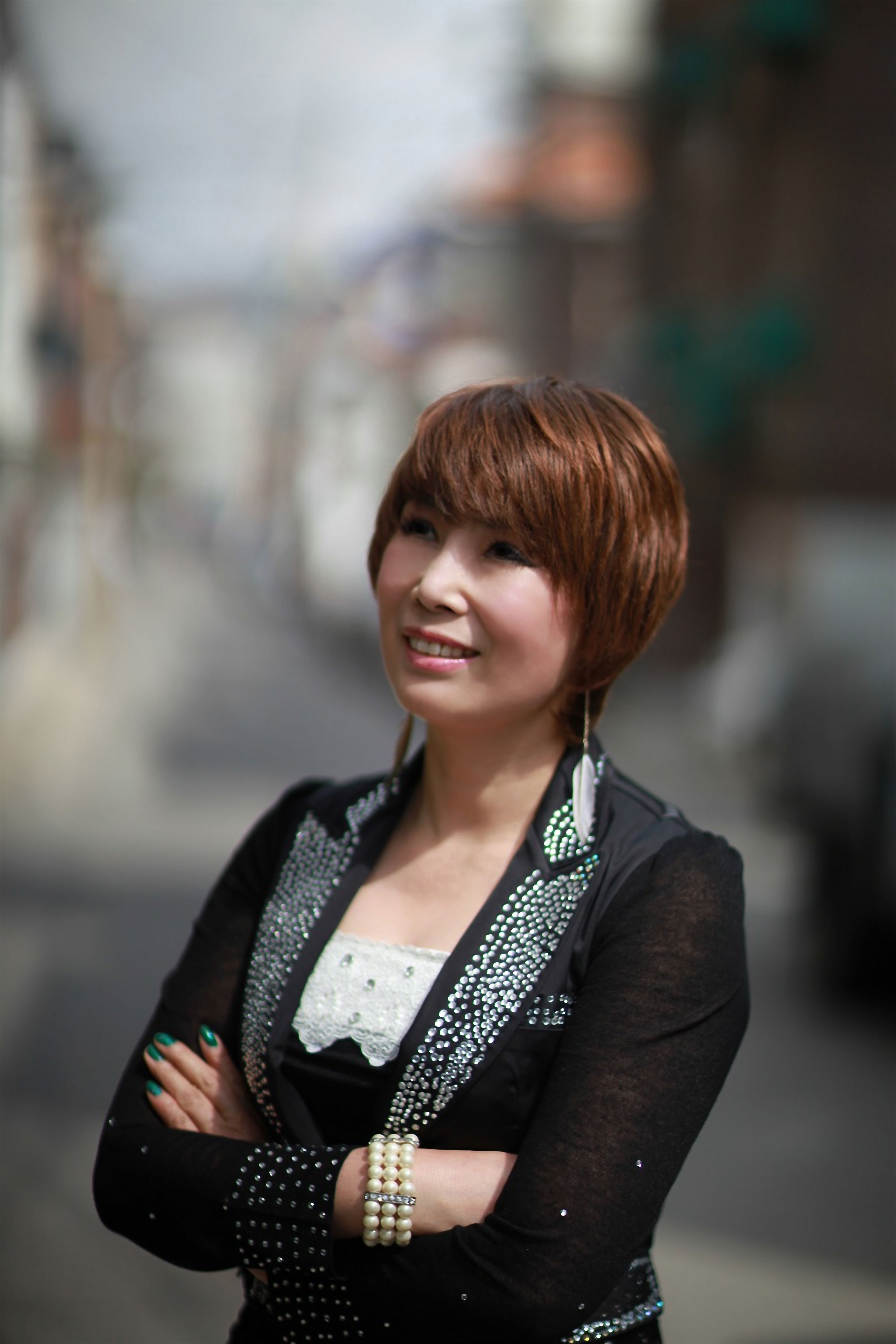 Smiling woman with short hair standing outdoors in a city street.