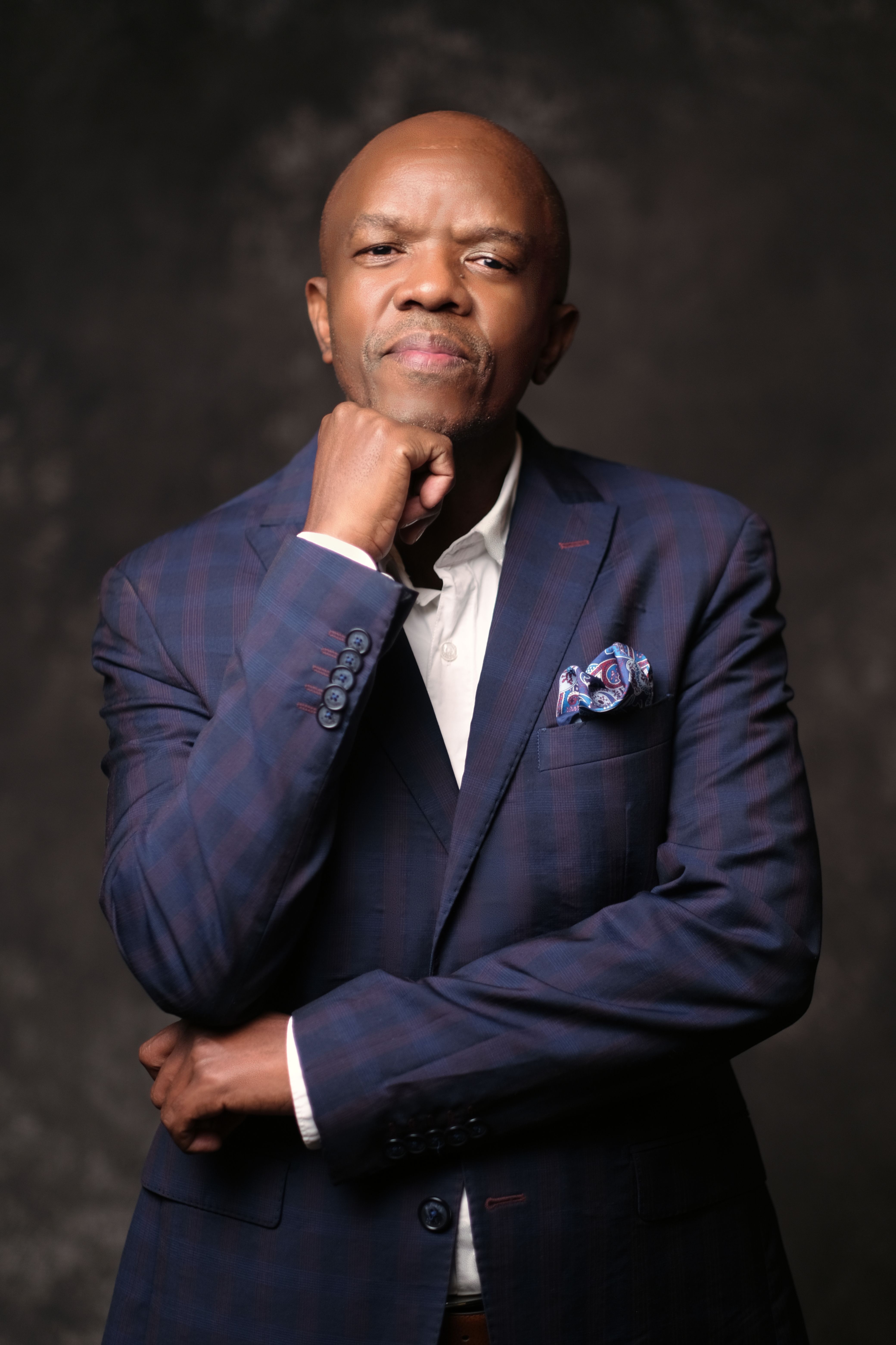 Stylish man in a blue suit posing confidently in a studio portrait.
