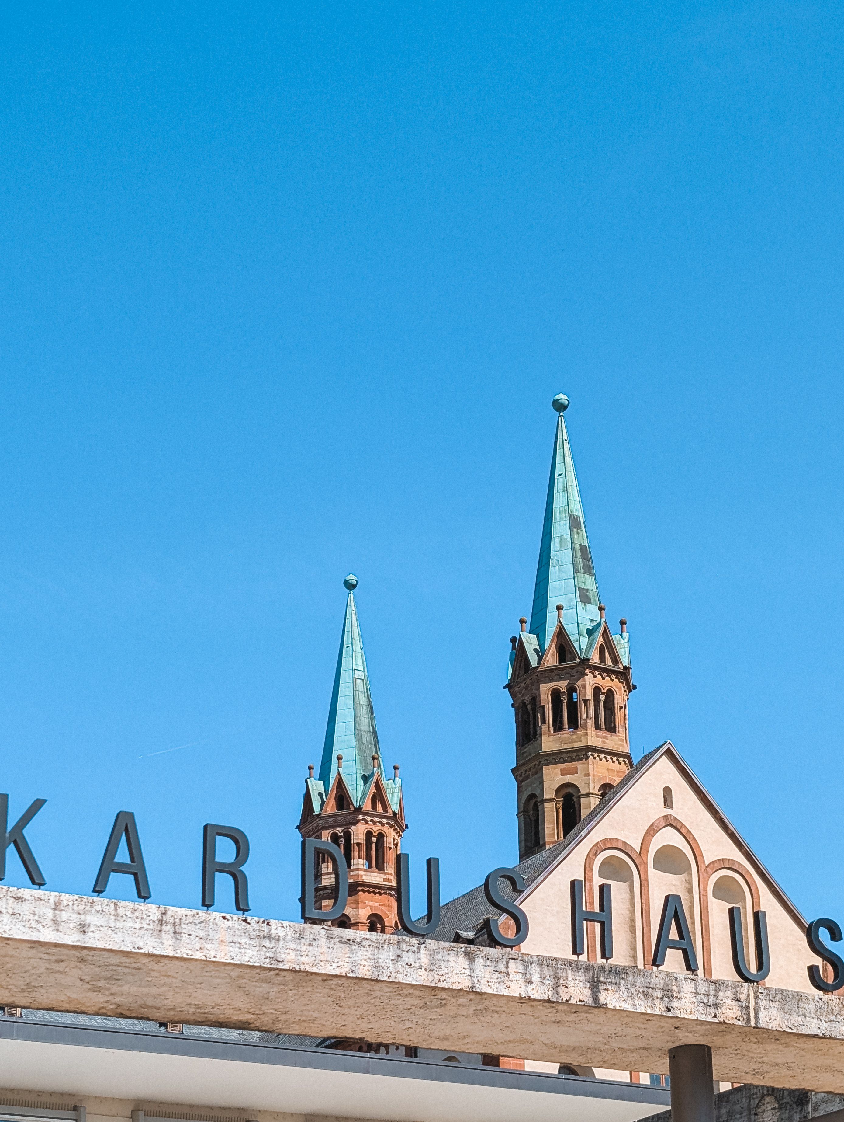 Twin church spires rise majestically in Würzburg, Germany, set against a clear blue sky.