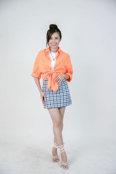 Smiling woman in orange top and stylish skirt poses in studio.