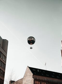 Hot air balloon floating above Berlin cityscape with clear sky in the background.