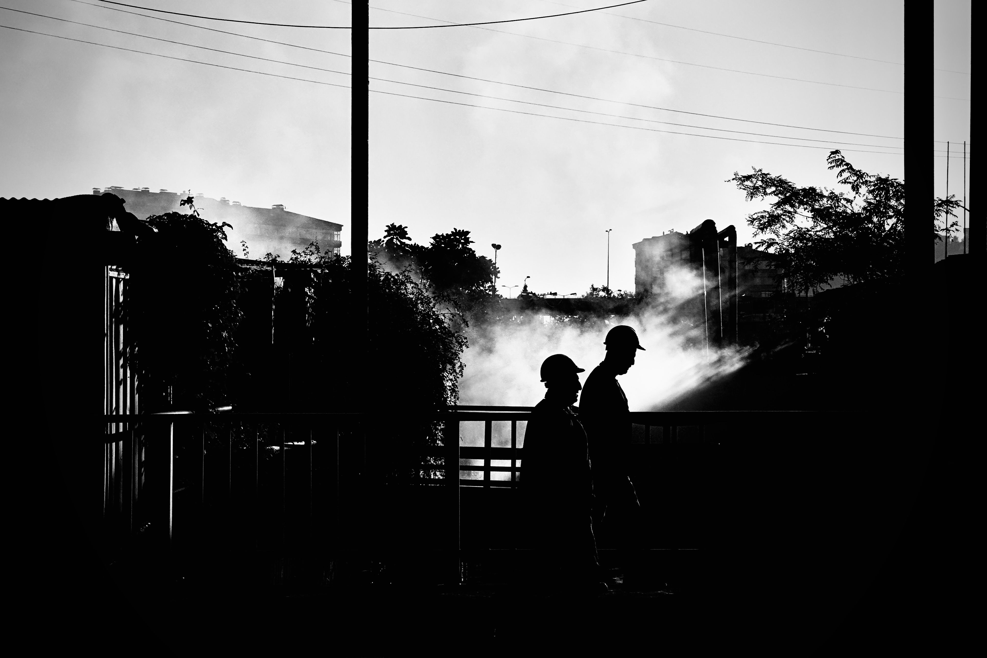 Silhouetted industrial workers in a factory setting with smoke in the background.