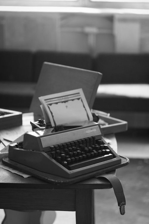Free A black and white photo of a vintage typewriter on a wooden desk, evoking nostalgia. Stock Photo