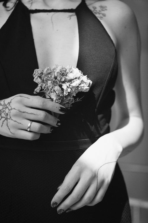 Free Black and white portrait of a woman holding flowers, showcasing elegance and tattoos. Stock Photo