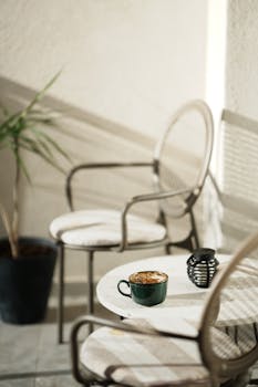 A cozy balcony in Kosovo with chairs, coffee, and sunlight creating a relaxing atmosphere.