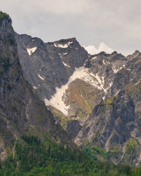 Breathtaking view of a rugged mountain range with snow-capped peaks and lush greenery.