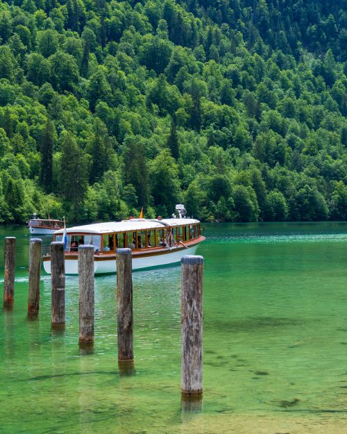 Free Scenic view of a tranquil boat ride on a clear mountain lake surrounded by lush forest. Stock Photo