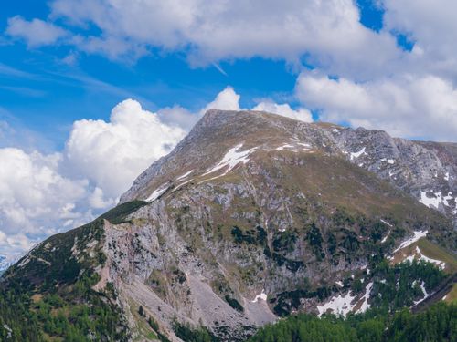 Free Breathtaking view of a rugged alpine mountain with snow patches under a vibrant blue sky. Stock Photo