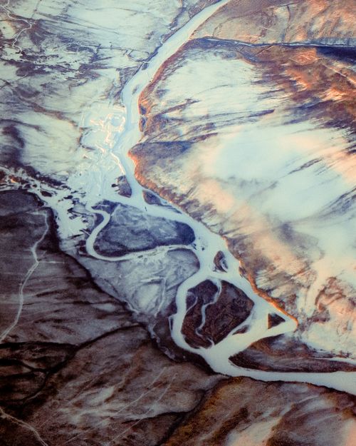 Free Stunning aerial shot of a winding river carving through a snow-covered winter landscape. Stock Photo