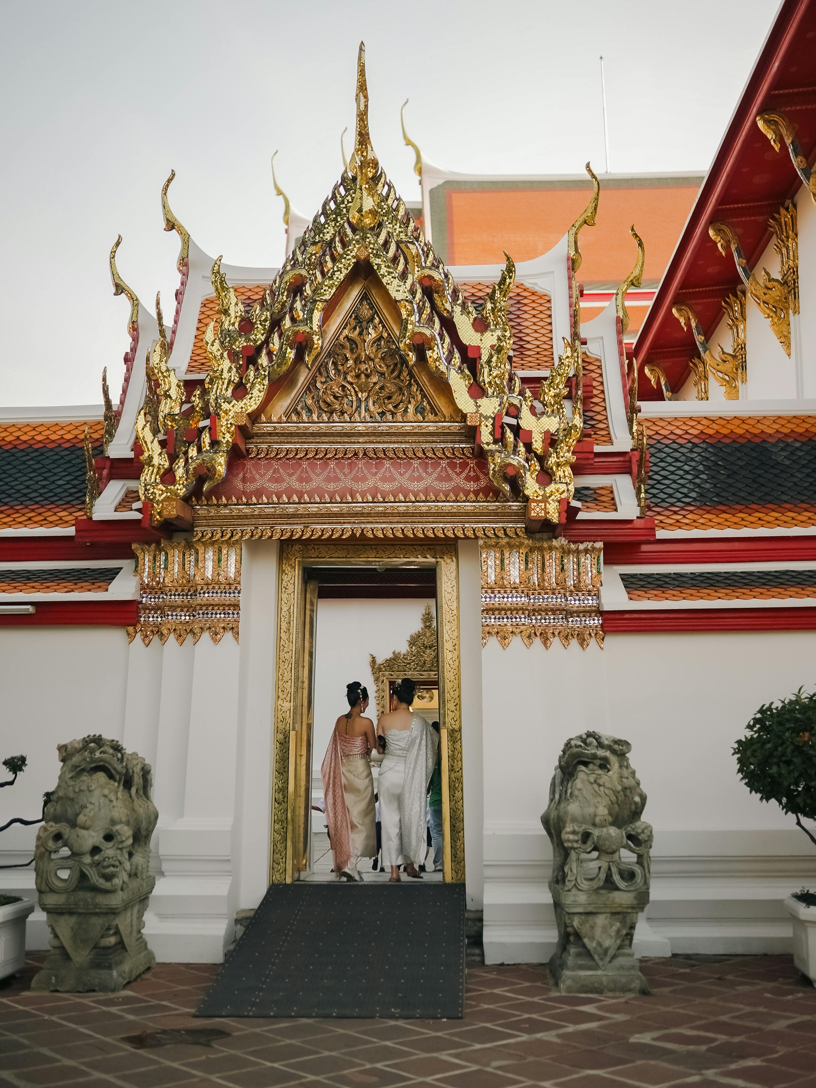 Traditional Thai architecture with intricate designs at a temple in Bangkok, Thailand, featuring visitors in traditional attire.