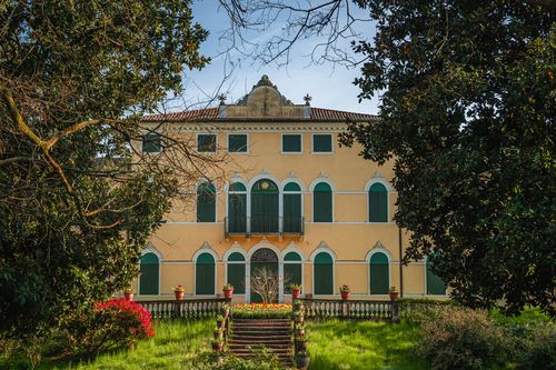 Free Beautiful historic villa surrounded by lush greenery and vibrant spring flowers in a serene setting. Stock Photo