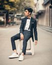 一个穿着燕尾礼服的时尚男人坐在城市街边