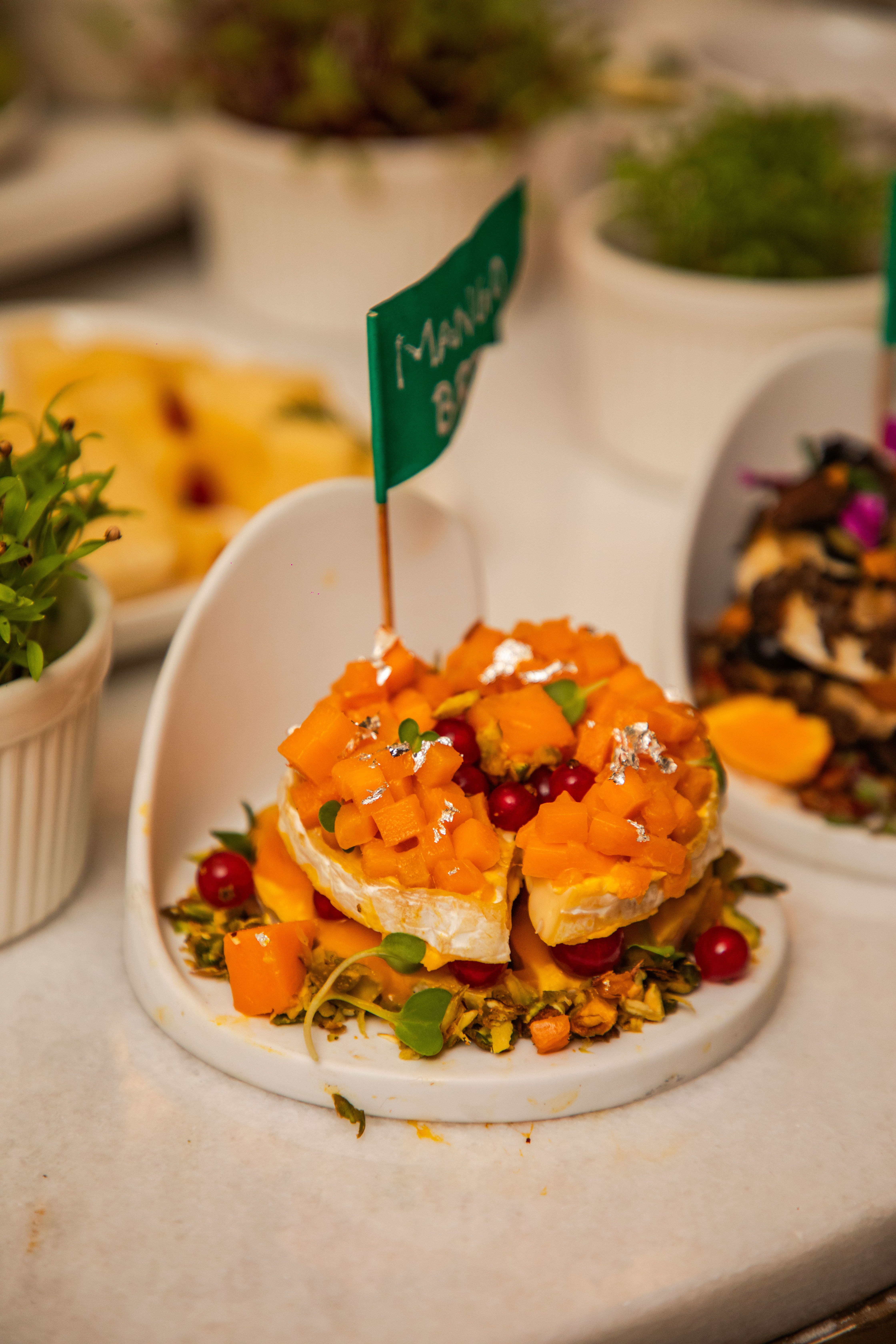 Vibrant mango bruschetta garnished with pomegranate and microgreens on a white plate.