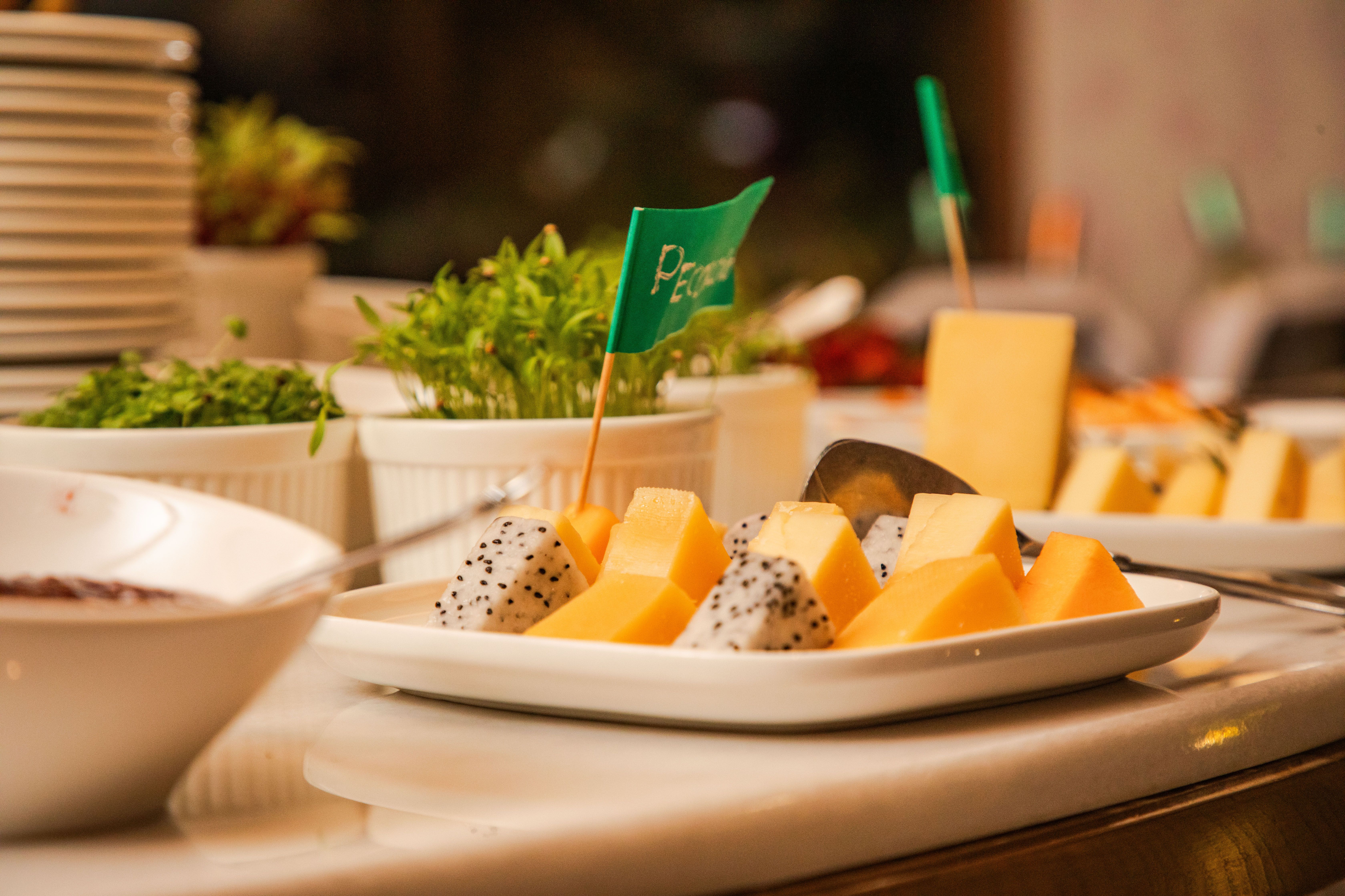 A vibrant fruit platter featuring slices of dragon fruit and melon on a buffet table with fresh herbs.