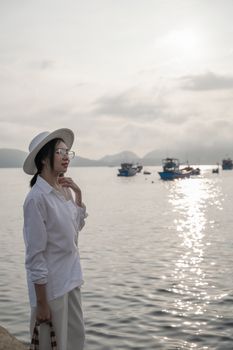 Woman in white enjoys a peaceful seaside sunrise view.