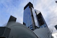 从低角度仰望，一座采用未来主义设计元素的时尚摩天大楼矗立在多云的天空下