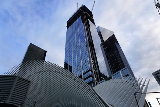 从低角度仰望，一座采用未来主义设计元素的时尚摩天大楼矗立在多云的天空下