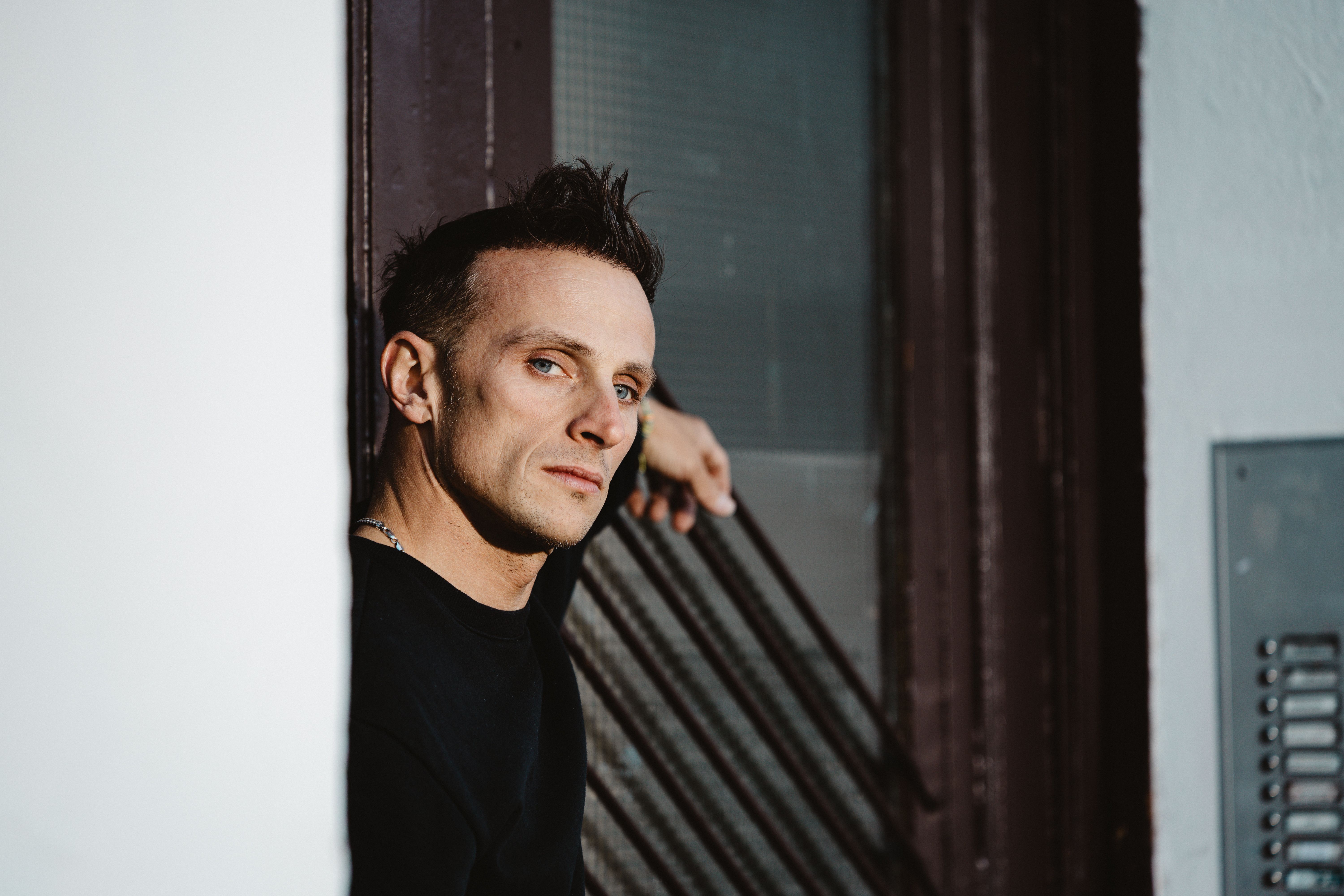 Candid portrait of a man leaning on a railing in Berlin, capturing a thoughtful expression.