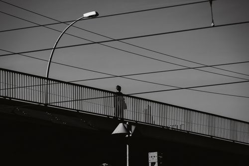 Free A striking black and white silhouette of a person standing on a bridge in Berlin, Germany. Stock Photo