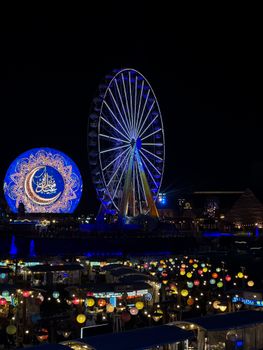 A vibrant Ferris wheel and illuminated lanterns at night create a festive ambiance, highlighting cultural celebration.