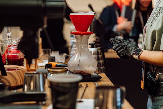 Close-up of barista crafting pour-over coffee in a bustling Baku cafe.