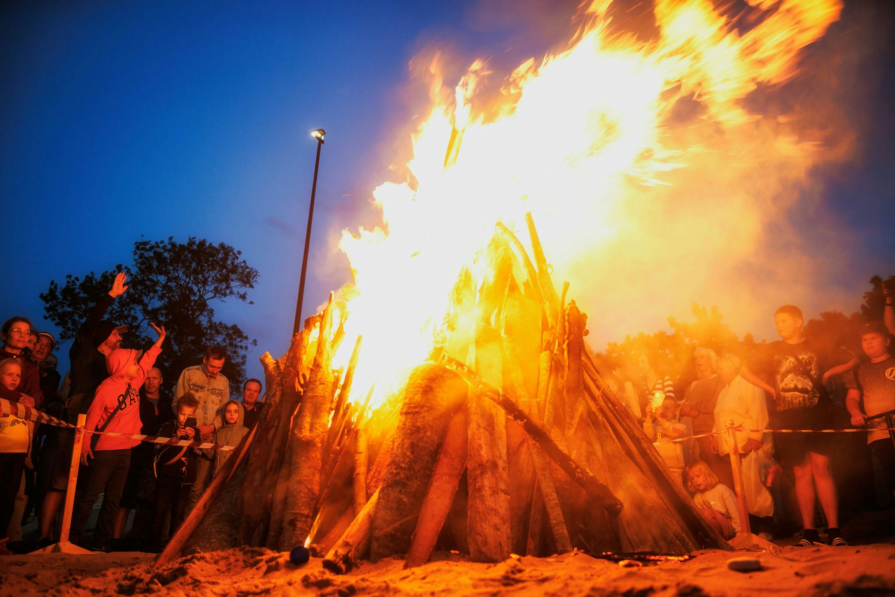 People gathered around a large bonfire during a festive outdoor evening event.