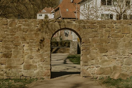 Free Vintage stone wall with archway leading to a modern urban area. Stock Photo